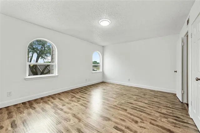 a view of an empty room with window and wooden floor