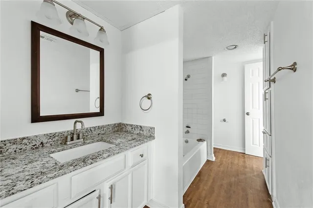 a en suite bathroom with a granite countertop sink and a mirror