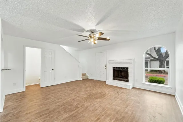 an empty room with fireplace and ceiling fan