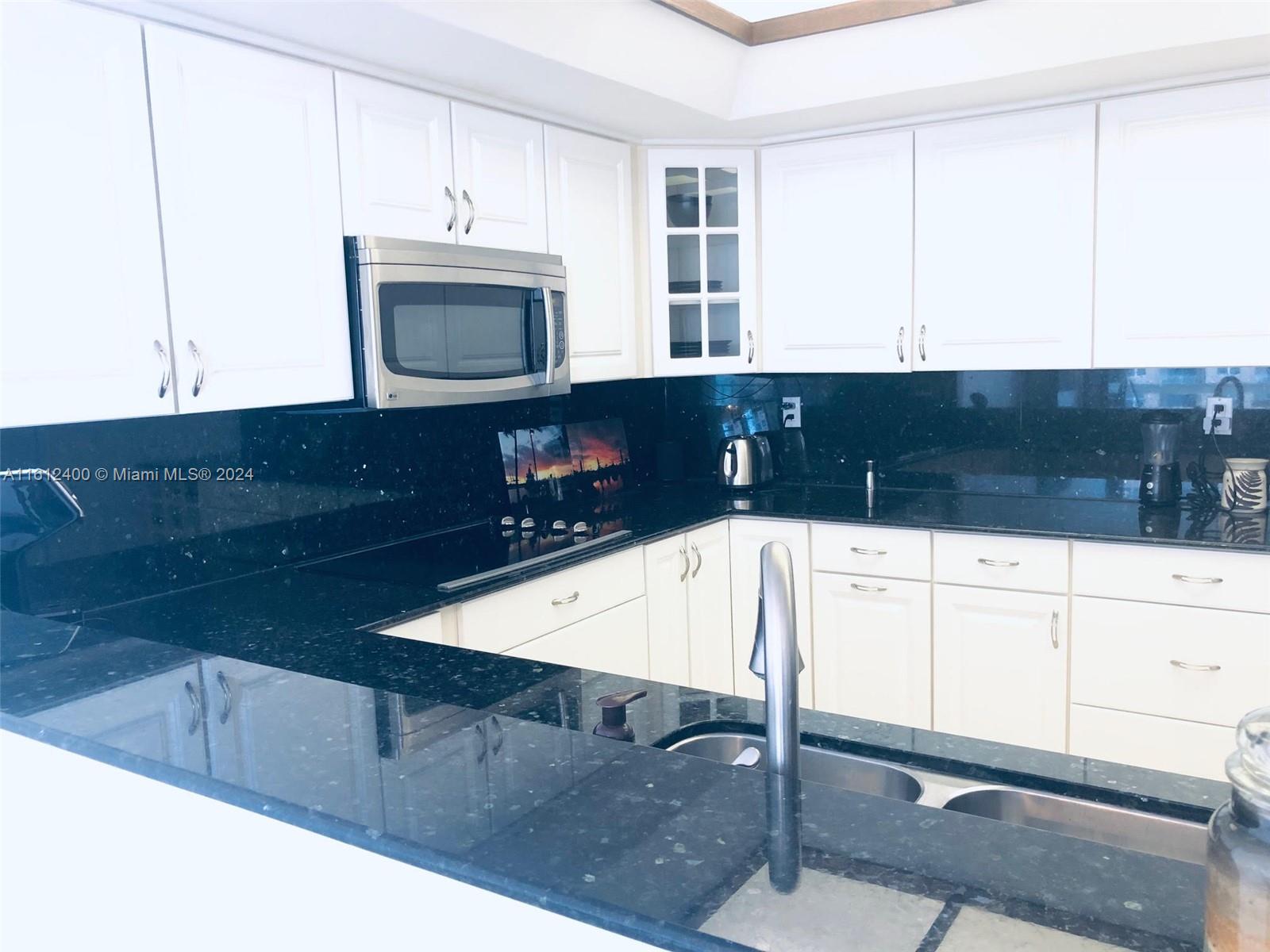 520 Brickell Key Drive, Unit A1005 Miami, FL 33131 - Photo 8 of 20 a kitchen with a sink a microwave a stove and cabinets