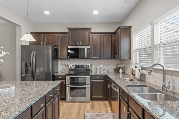 a kitchen with kitchen island granite countertop stainless steel appliances a sink dishwasher a refrigerator a stove top oven and a center island