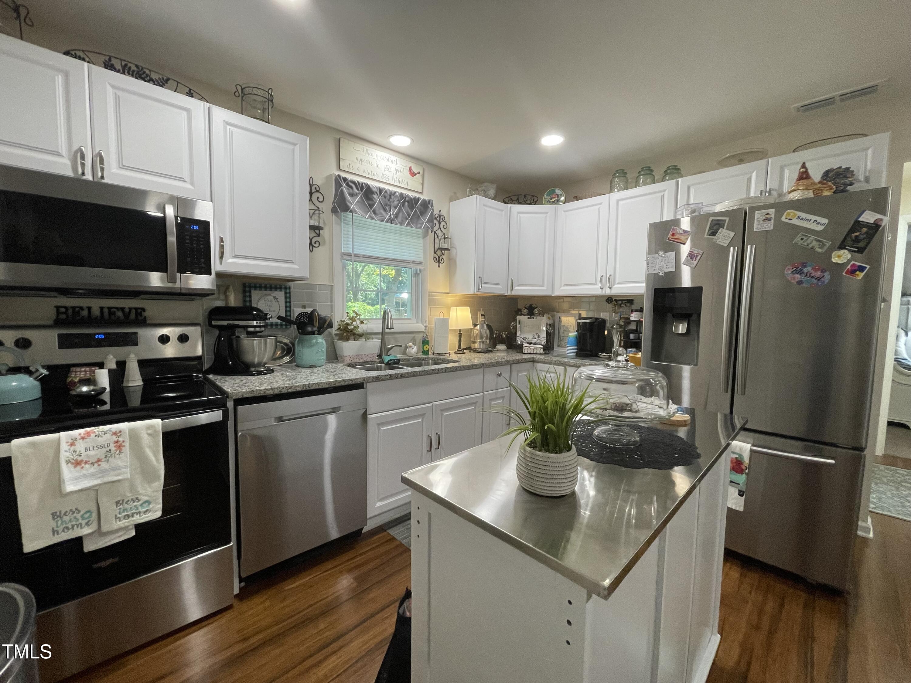 204 Jackson Street Dunn, NC 28334 - Photo 37 of 49 a kitchen with stainless steel appliances a stove a sink a refrigerator a microwave and cabinets