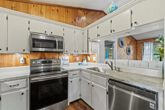 a kitchen with granite countertop a sink stainless steel appliances and cabinets