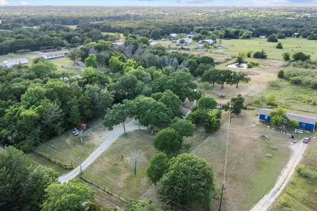 an aerial view of residential houses with outdoor space and trees