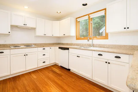 a kitchen with granite countertop white cabinets and white appliances