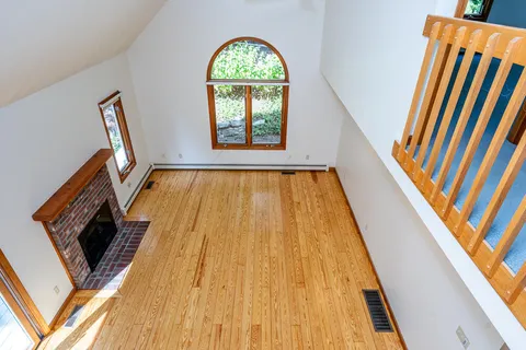 a view of an empty room with wooden floor and a fireplace