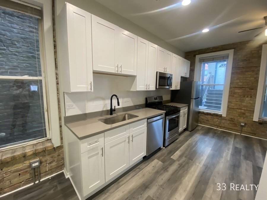 1246 North Cleaver Street, Unit GR Chicago, IL 60642 - Photo 2 of 7 a kitchen with a sink stove and cabinets