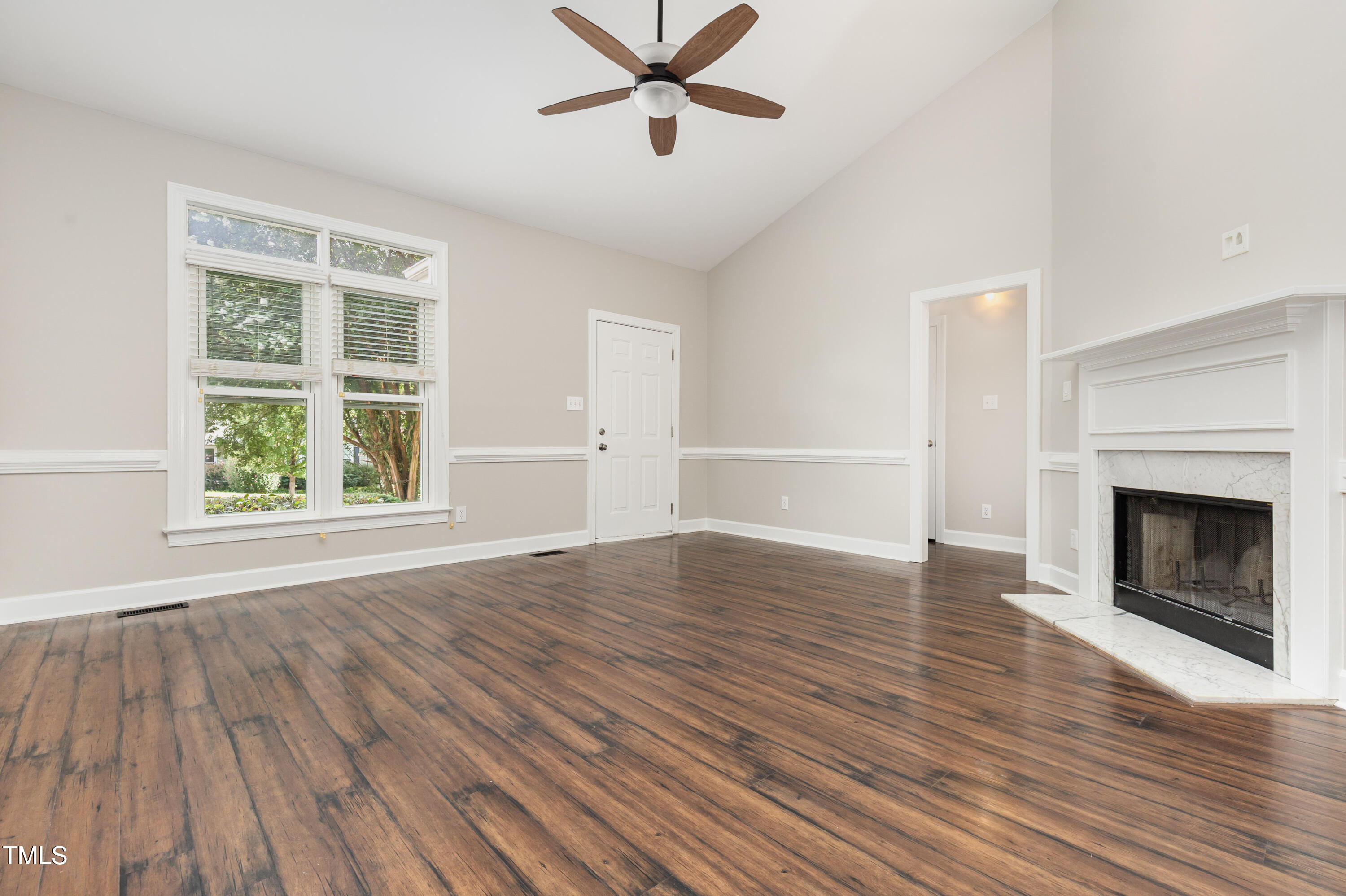 9316 Dawnshire Road Raleigh, NC 27615 - Photo 11 of 31 an empty room with wooden floor a fireplace and windows
