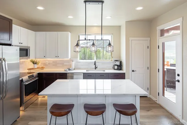 a kitchen with a dining table chairs and refrigerator