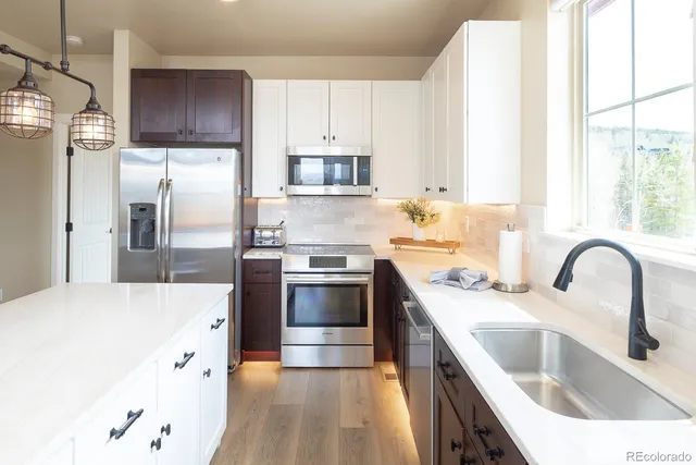 a kitchen with stainless steel appliances granite countertop a sink a stove and refrigerator