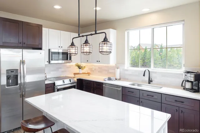 a kitchen with granite countertop a sink a counter space appliances and cabinets