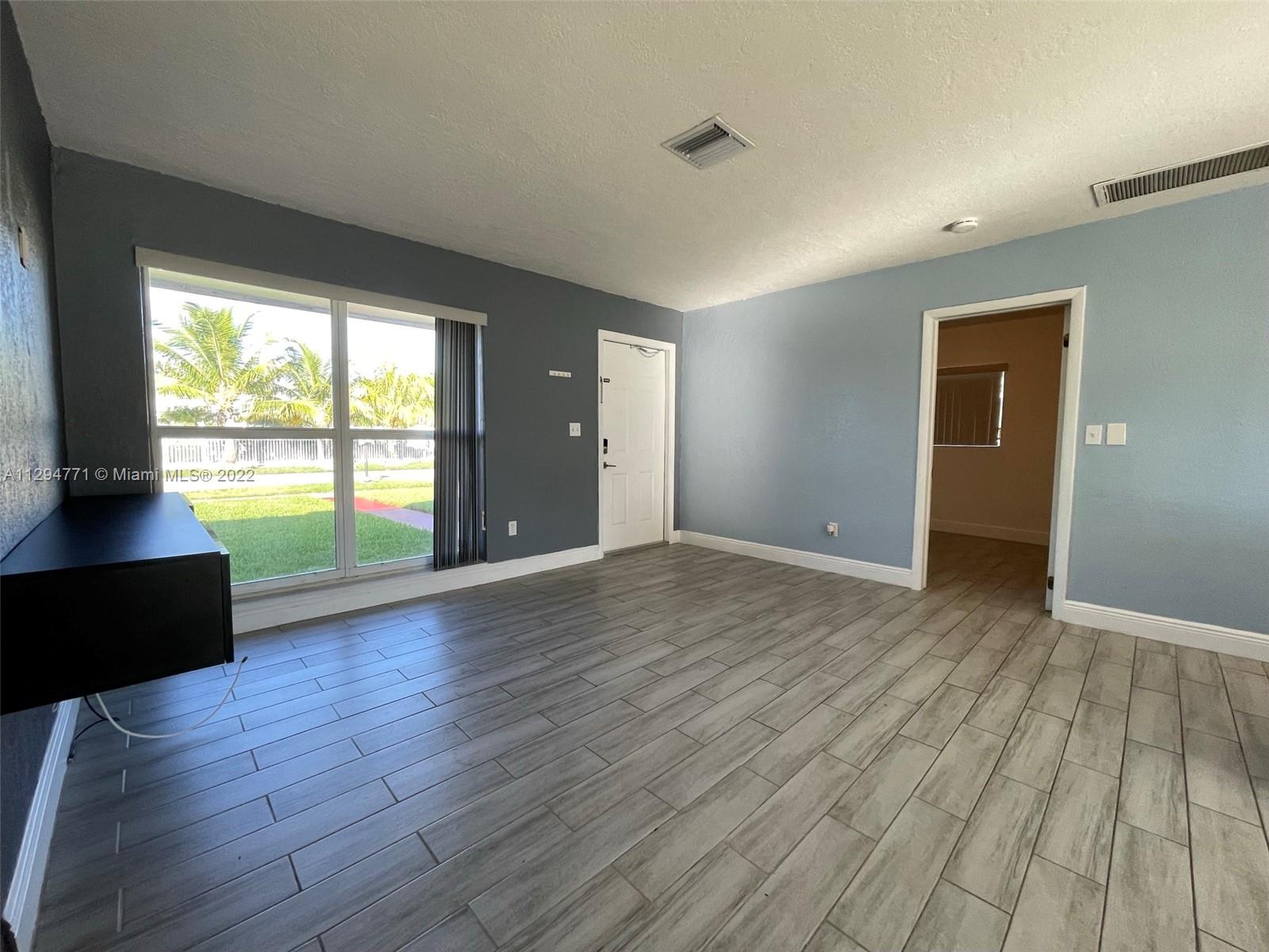 14515 Southwest 105th Court Miami, FL 33176 - Photo 4 of 30 an empty room with wooden floor and windows