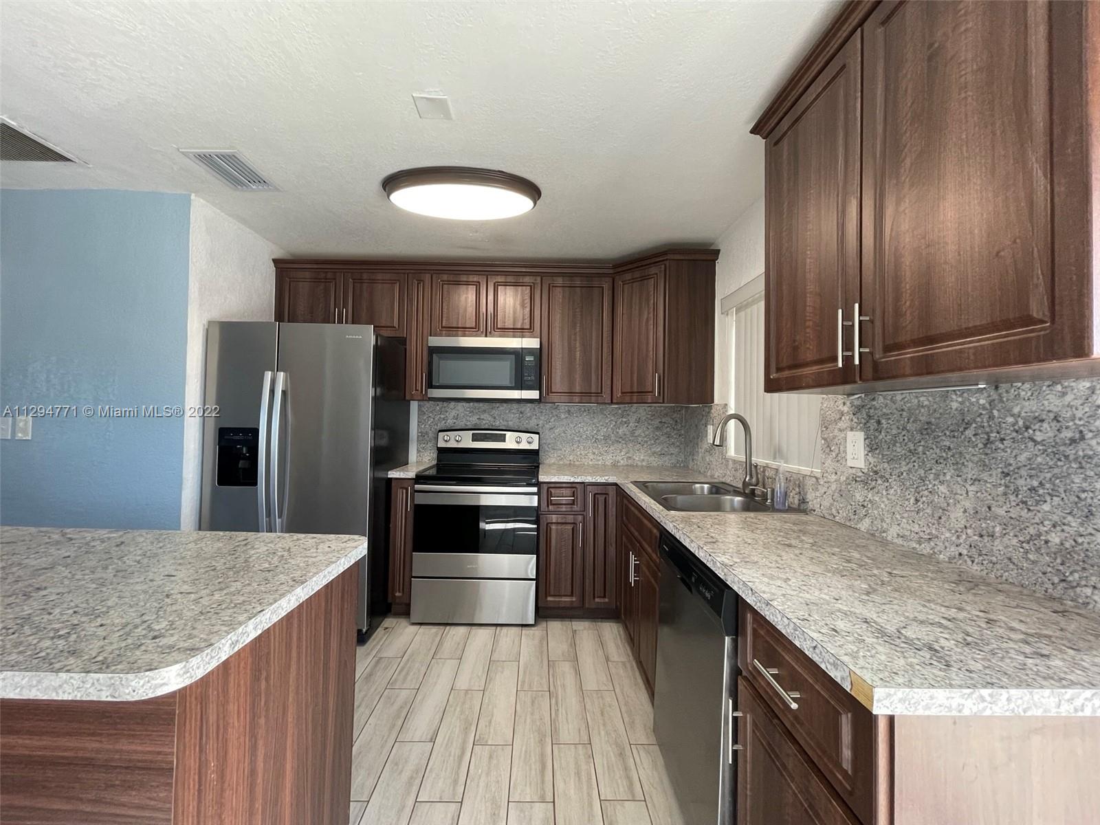 14515 Southwest 105th Court Miami, FL 33176 - Photo 7 of 30 a kitchen with stainless steel appliances granite countertop a sink stove microwave and refrigerator