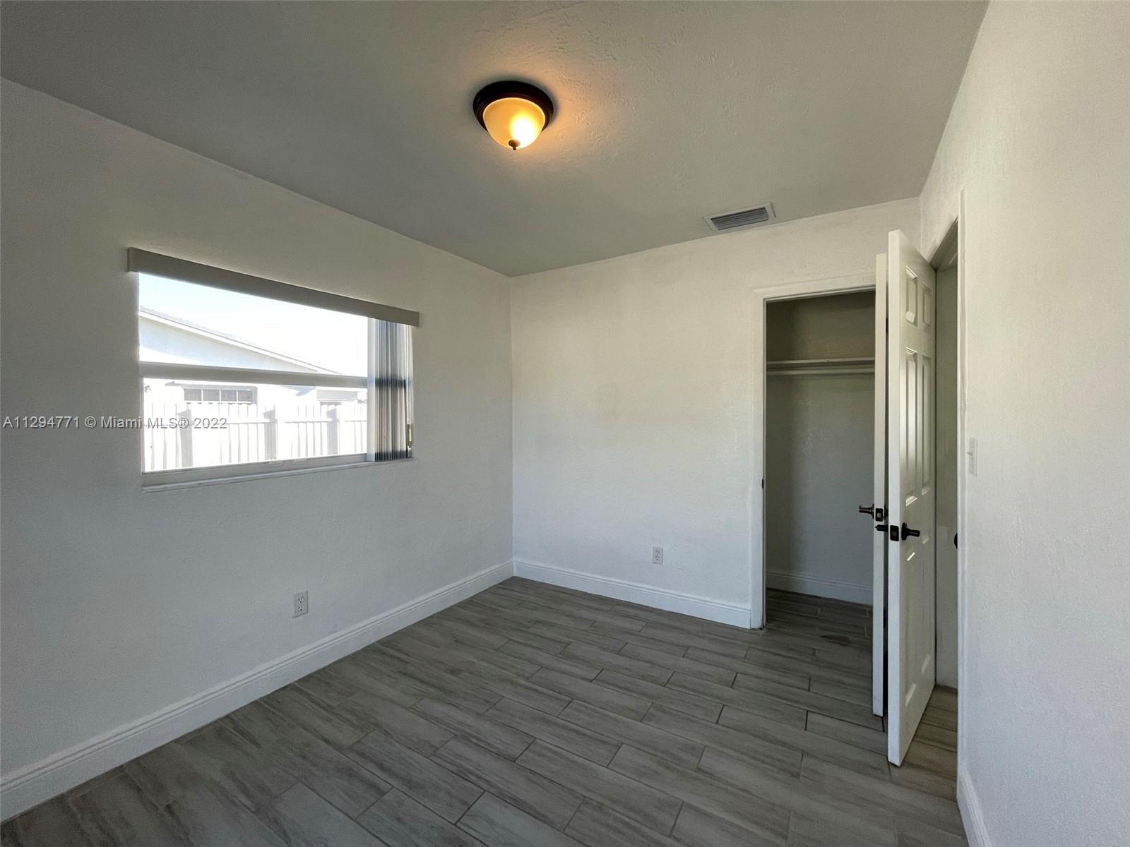 14515 Southwest 105th Court Miami, FL 33176 - Photo 10 of 30 an empty room with wooden floor and windows