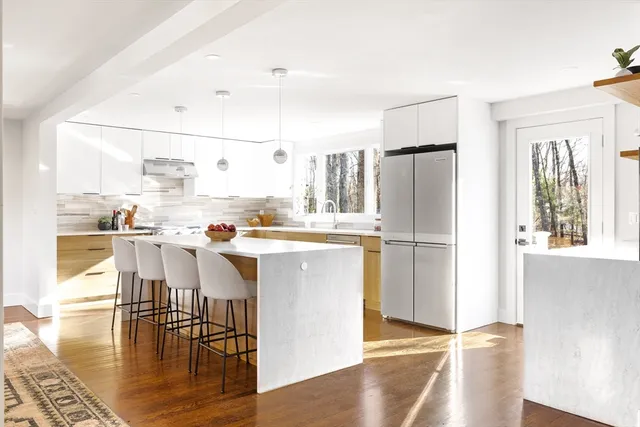 a kitchen with stainless steel appliances granite countertop a refrigerator a stove and a dining table with wooden floor