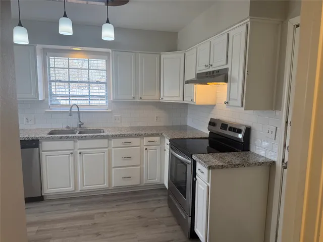 a kitchen with granite countertop cabinets stainless steel appliances a sink and a window