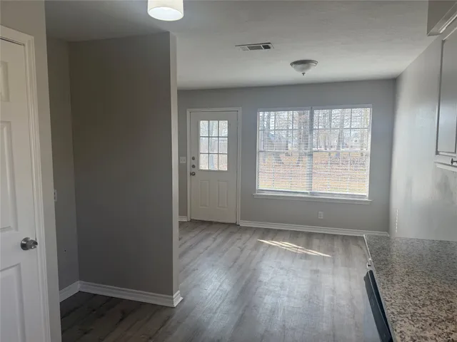 an empty room with wooden floor and windows