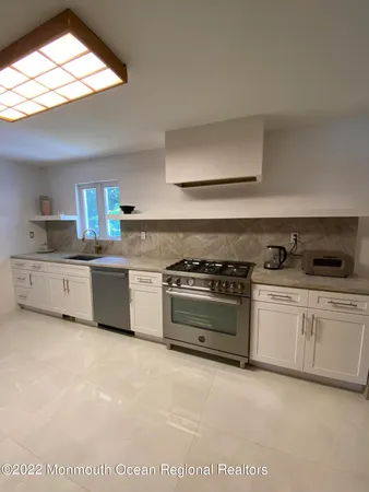 a kitchen with stainless steel appliances a stove a sink and white cabinets