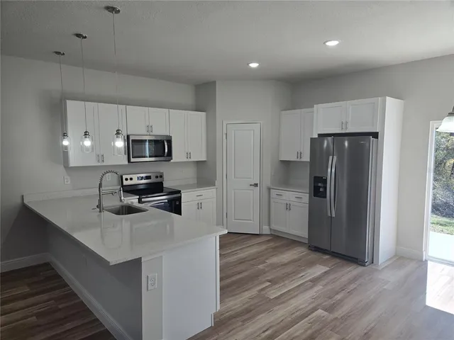 a kitchen with a refrigerator a stove top oven and wooden floor