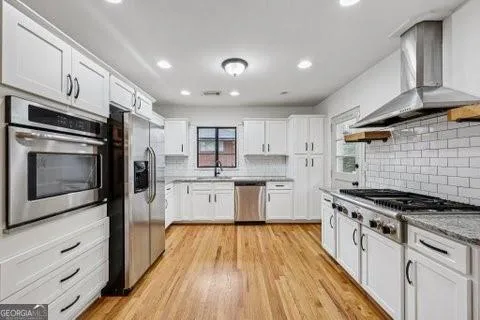 a kitchen with stainless steel appliances a refrigerator a stove and white cabinets