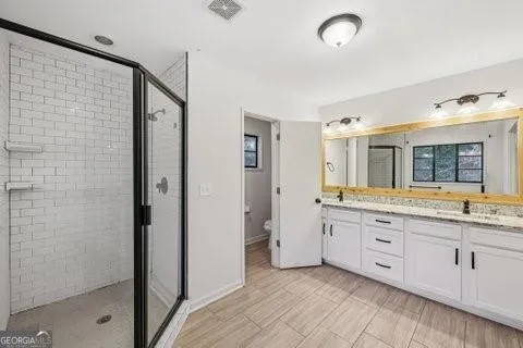 a spacious bathroom with a granite countertop sink a mirror and a shower
