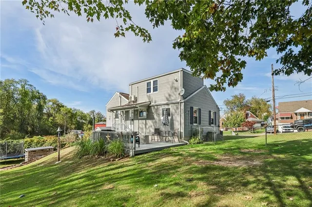 a view of a house with a big yard plants and large trees