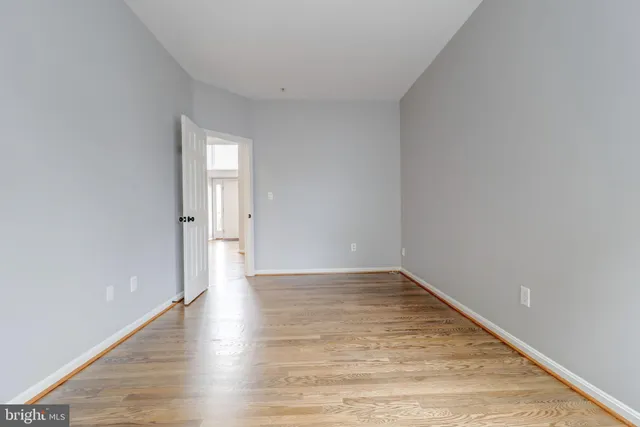 an empty room with wooden floor and windows with curtains view