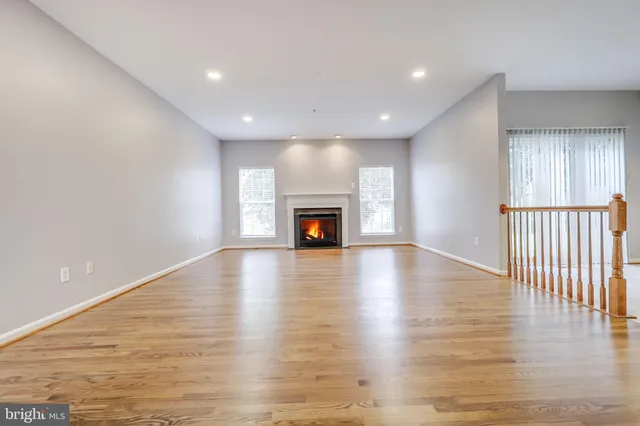 a kitchen with stainless steel appliances granite countertop a refrigerator a sink dishwasher a stove and a large window with wooden floor