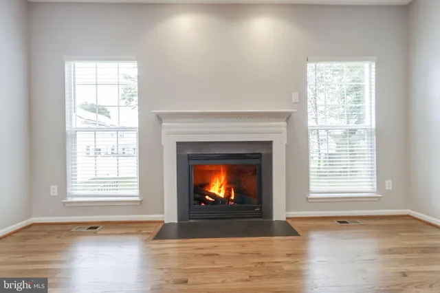 a kitchen with stainless steel appliances granite countertop a refrigerator a sink a stove and white cabinets with wooden floor