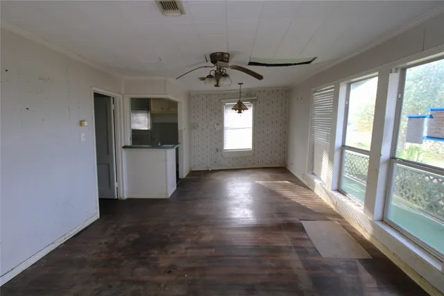 an empty room with windows and ceiling fan