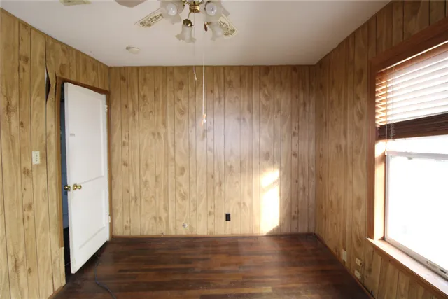 a view of empty room with wooden floor and fan
