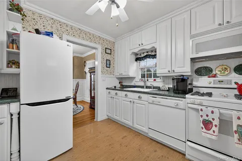 a kitchen with stainless steel appliances granite countertop a refrigerator a sink a stove a dining table and chairs with wooden floor