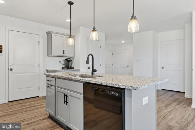 a kitchen with stainless steel appliances granite countertop a refrigerator a stove a sink dishwasher a oven and a dining table with wooden floor