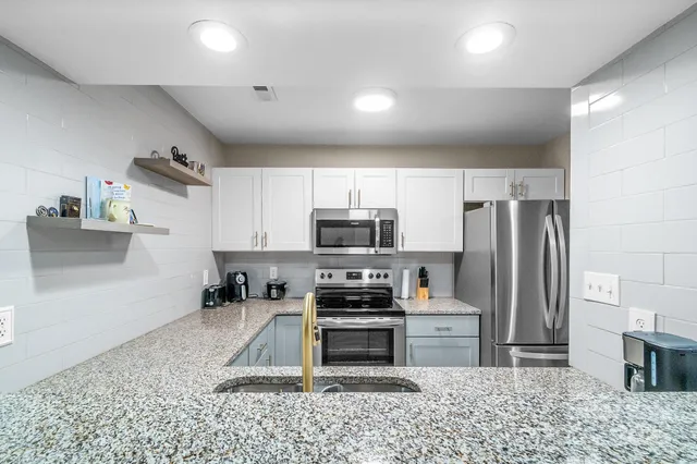 a kitchen with granite countertop a refrigerator and a stove top oven