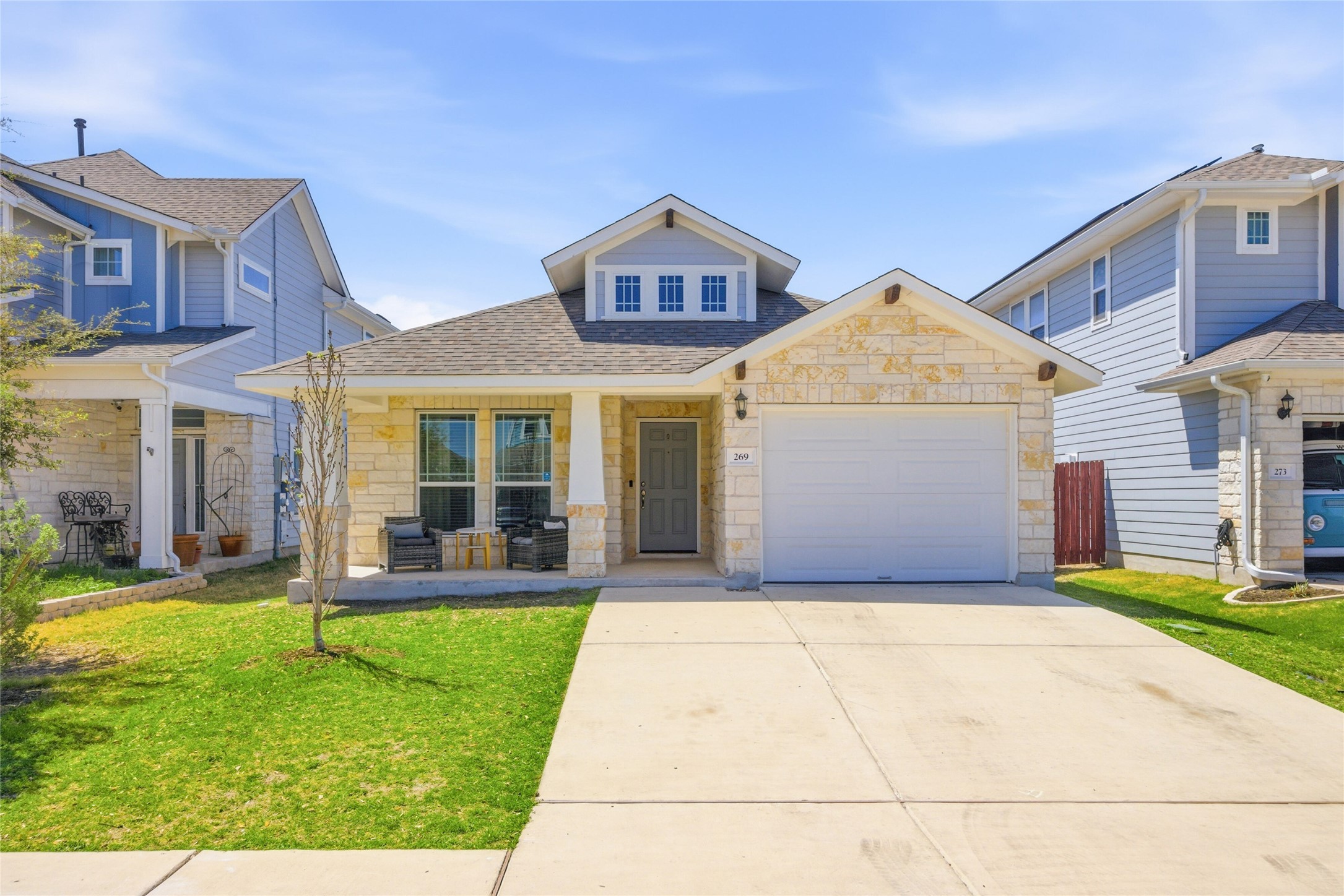 269 Gaida Loop Georgetown, TX 78628 - Photo 2 of 20 View of front of property with stone siding, covered porch, a front lawn, a garage, and concrete driveway