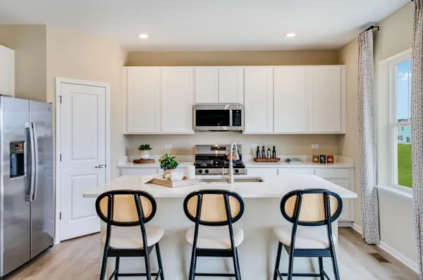 a kitchen with stainless steel appliances a dining table chairs refrigerator and sink