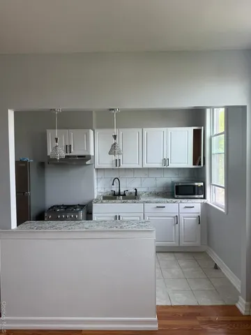 a kitchen with granite countertop a sink a stove and cabinets