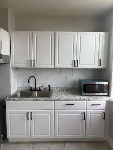 a kitchen with white cabinets a sink and white appliances