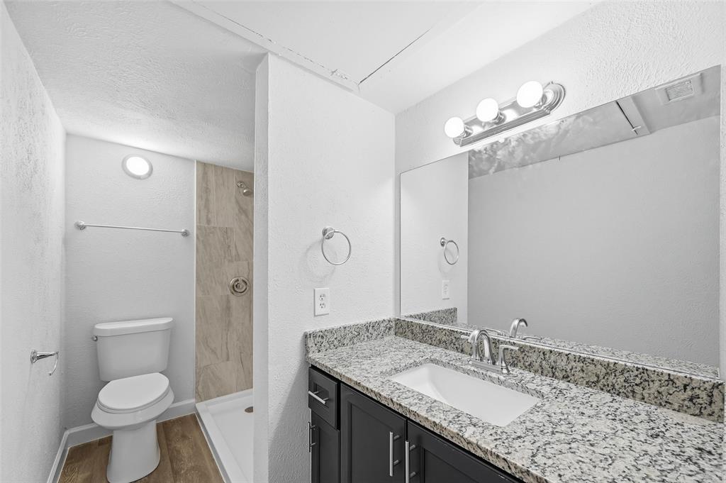 4859 Cedar Springs Road, Unit 136 Dallas, TX 75219 - Photo 18 of 28 a bathroom with a granite countertop sink a toilet and a mirror