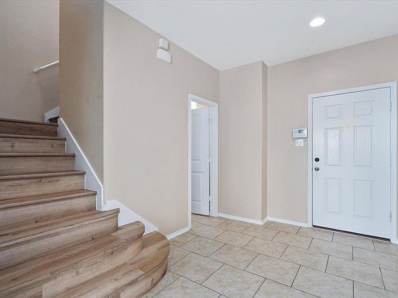 904 Lonesome Lilly Way Pflugerville, TX 78660 - Photo 15 of 34 The foyer features light-colored tile flooring, a white paneled door, and a staircase with wood-look risers and treads