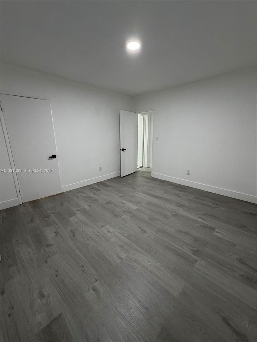 324 Surfside Boulevard, Unit 7 Surfside, FL 33154 - Photo 5 of 8 an empty room with wooden floor and windows