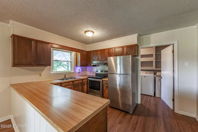 a kitchen with kitchen island a large counter top space stainless steel appliances and wooden floor