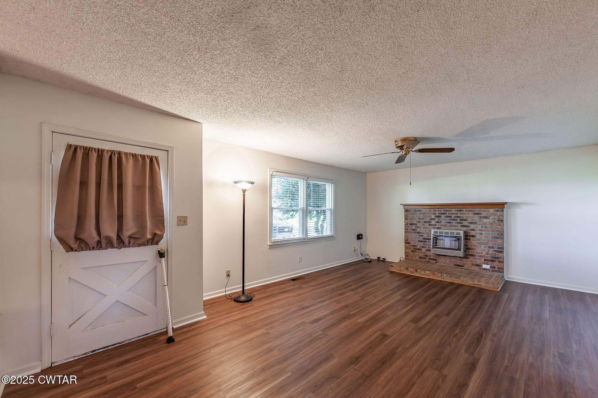 1140 Plainview Road Henderson, TN 38340 - Photo 20 of 29 an empty room with wooden floor fireplace and windows