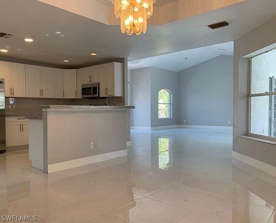 3353 Captains Cove Naples, FL 34112 - Photo 12 of 13 a kitchen with stainless steel appliances granite countertop a refrigerator a stove a sink and a microwave