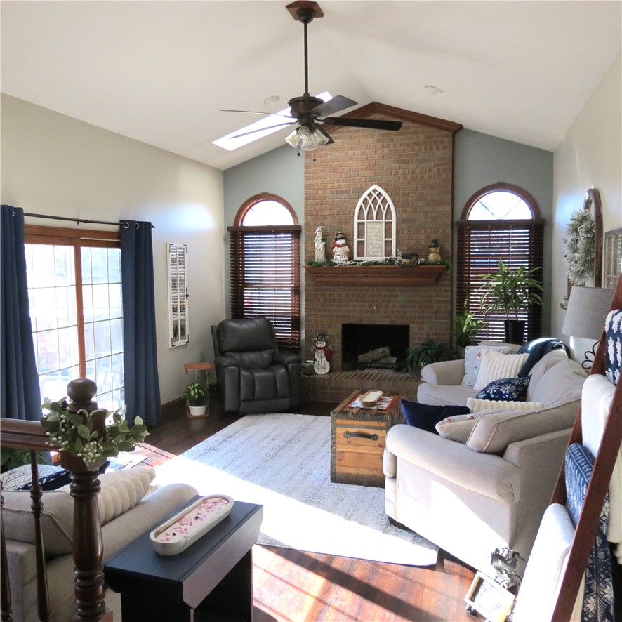 10160 Lochard Road Sidney, OH 45365 - Photo 8 of 41 This living room features vaulted ceilings and rich wood flooring, anchored by a prominent brick fireplace.