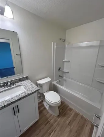 a bathroom with a granite countertop toilet a sink and a bathtub