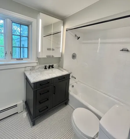 a bathroom with a sink vanity mirror bathtub and toilet