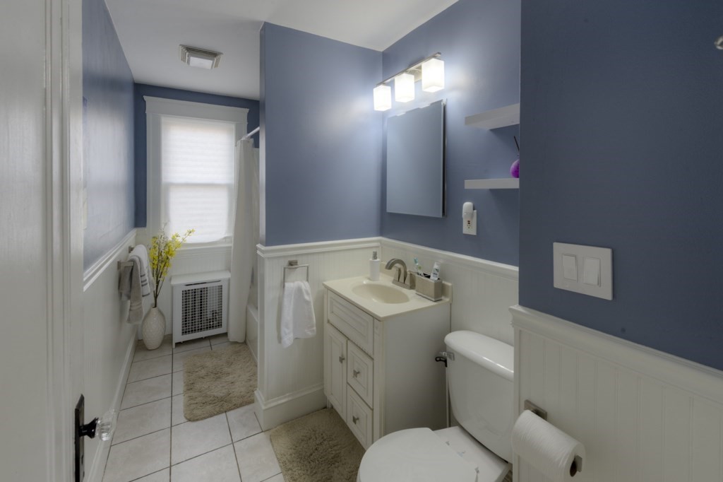 39 Woodford Street, Unit 3 Worcester, MA 01604 - Photo 21 of 37 a white toilet sitting next to a bathroom sink and a mirror