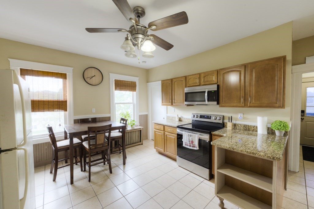 39 Woodford Street, Unit 3 Worcester, MA 01604 - Photo 24 of 37 a kitchen with stainless steel appliances granite countertop wooden cabinets a stove a sink a dining table and chairs