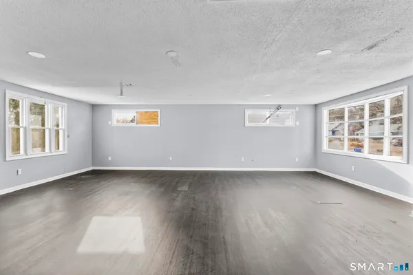 a view of an empty room with window and wooden floor